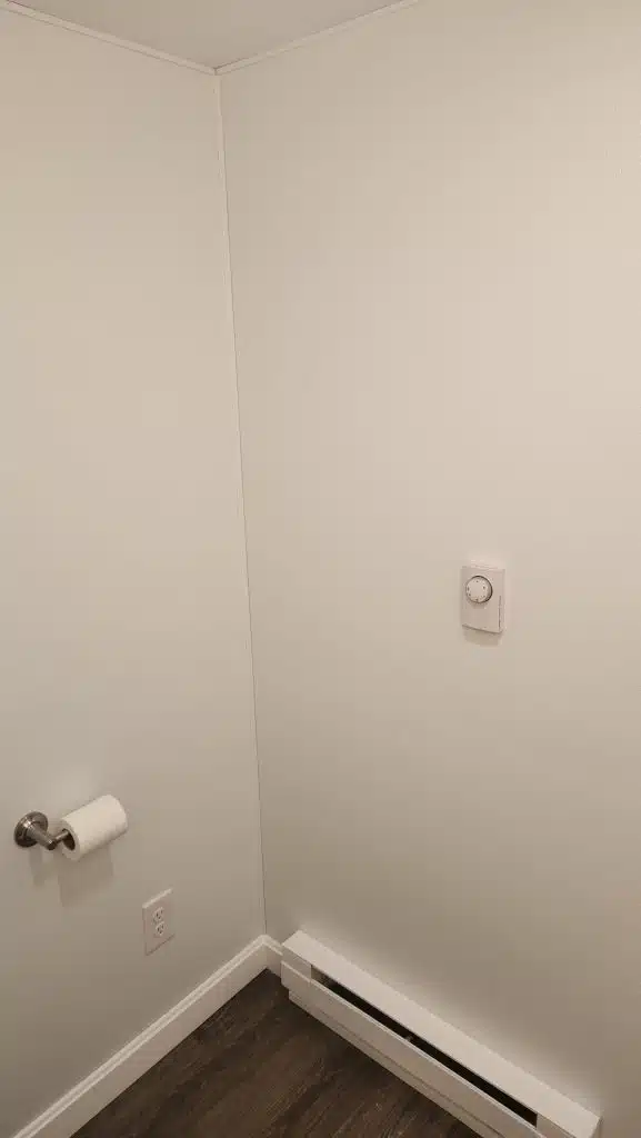 Electric baseboard heater with wall thermostat in a finished basement bathroom